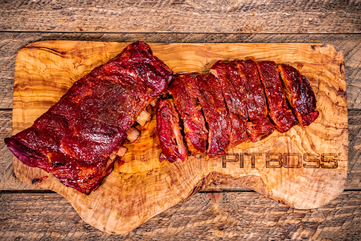 partially separated cooked ribs on wood pit boss cutting board