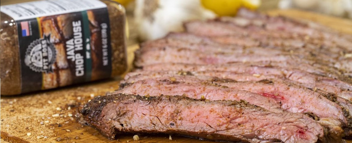 Sliced steak with Pit Boss Java chophouse rub bottle on wooden cutting board