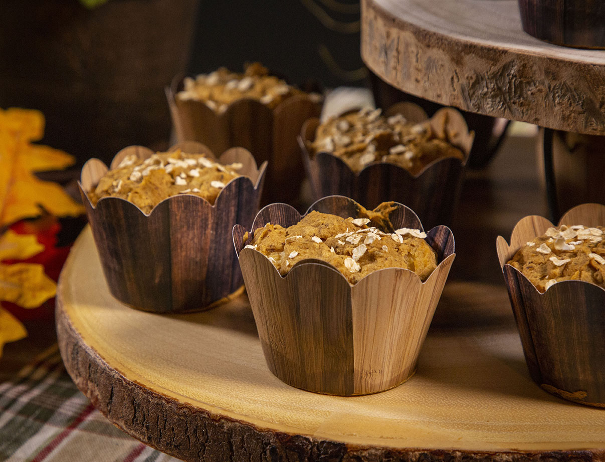 Apple pumpkin muffins on wooden cutting board with fall leaves and pumpkin decorations