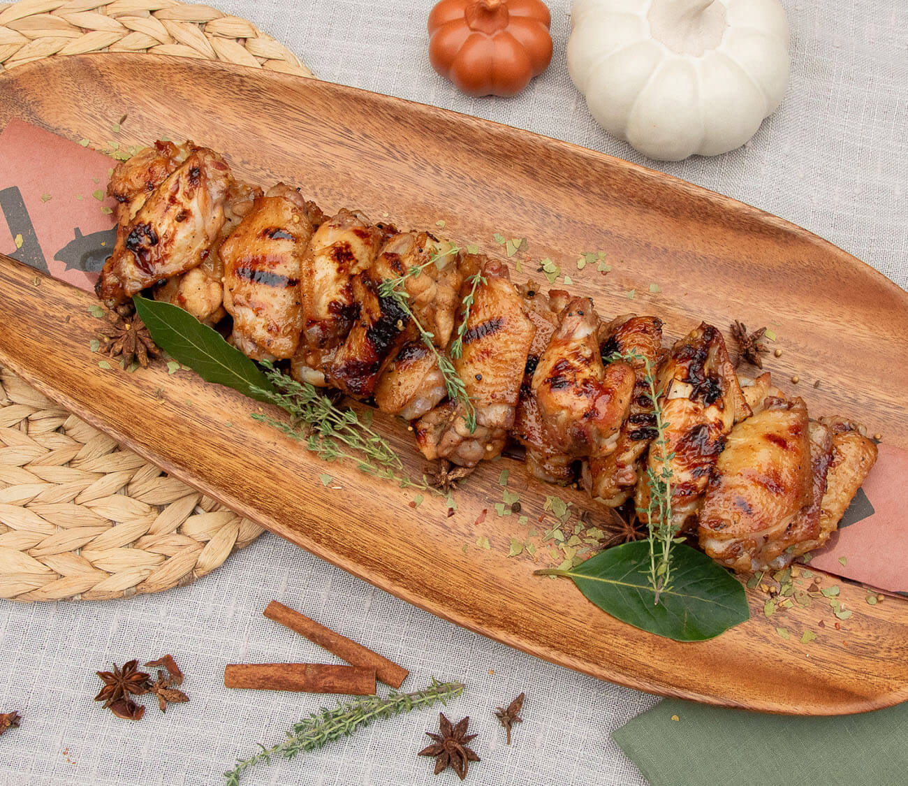 grilled chicken wings cooked on a pit boss wood pellet grill plated with fall seasonings like cinnamon, star anise and cloves with 2 decorative pumpkins