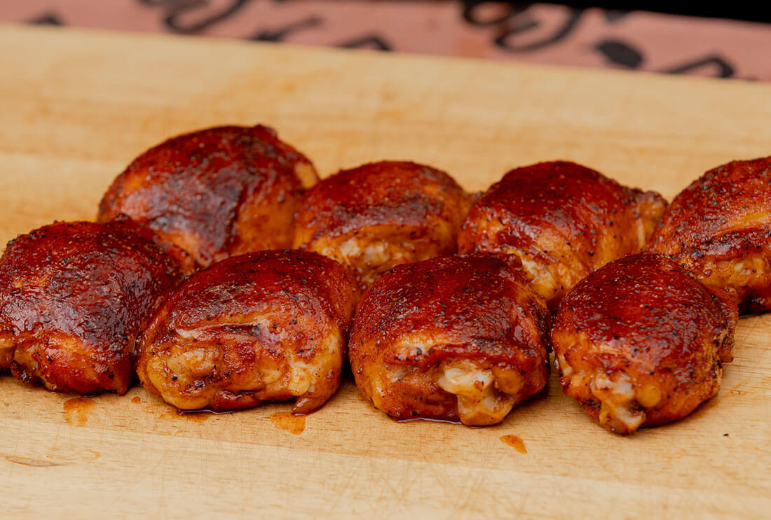 Smoked BBQ Chicken Thighs cooked on a Pit Boss wood pellet grill with BBQ rub and BBQ sauce on cutting board