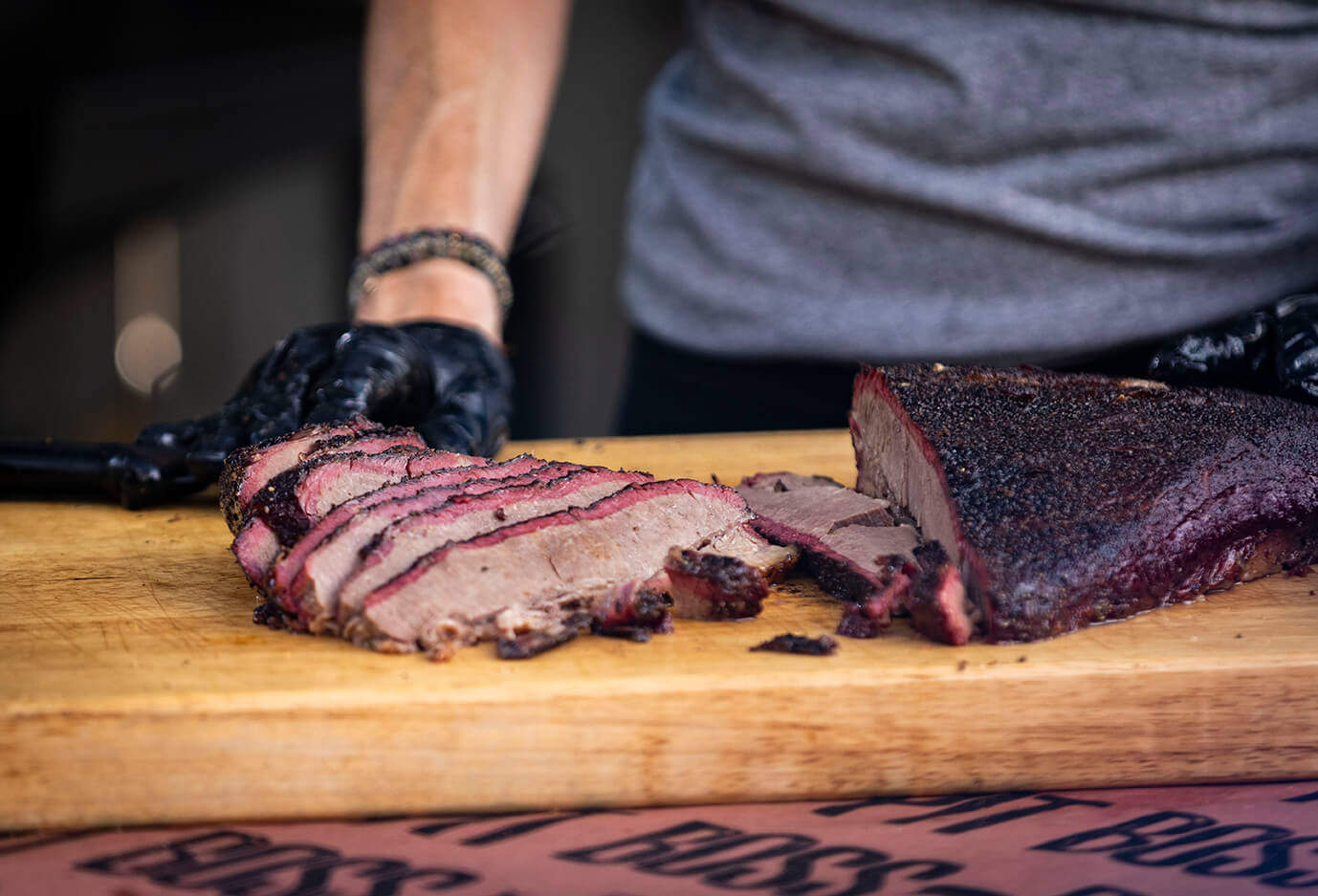 smoked competition-style brisket with smoke ring cooked on pit boss wood pellet grill. sliced thin on cutting board