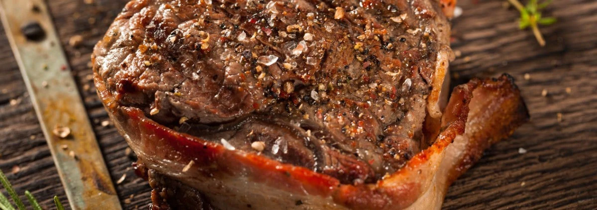 tasty looking Bacon Wrapped Steak with seasoning on a wood background