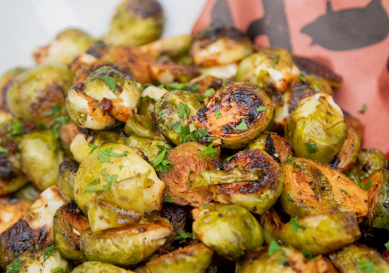 roasted brussels sprouts drizzled with a balsamic glaze, in a white bowl