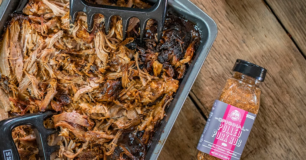 delicious looking Beer Braised pork butt in pan with pit boss meat claws and bottle of pulled pork rub