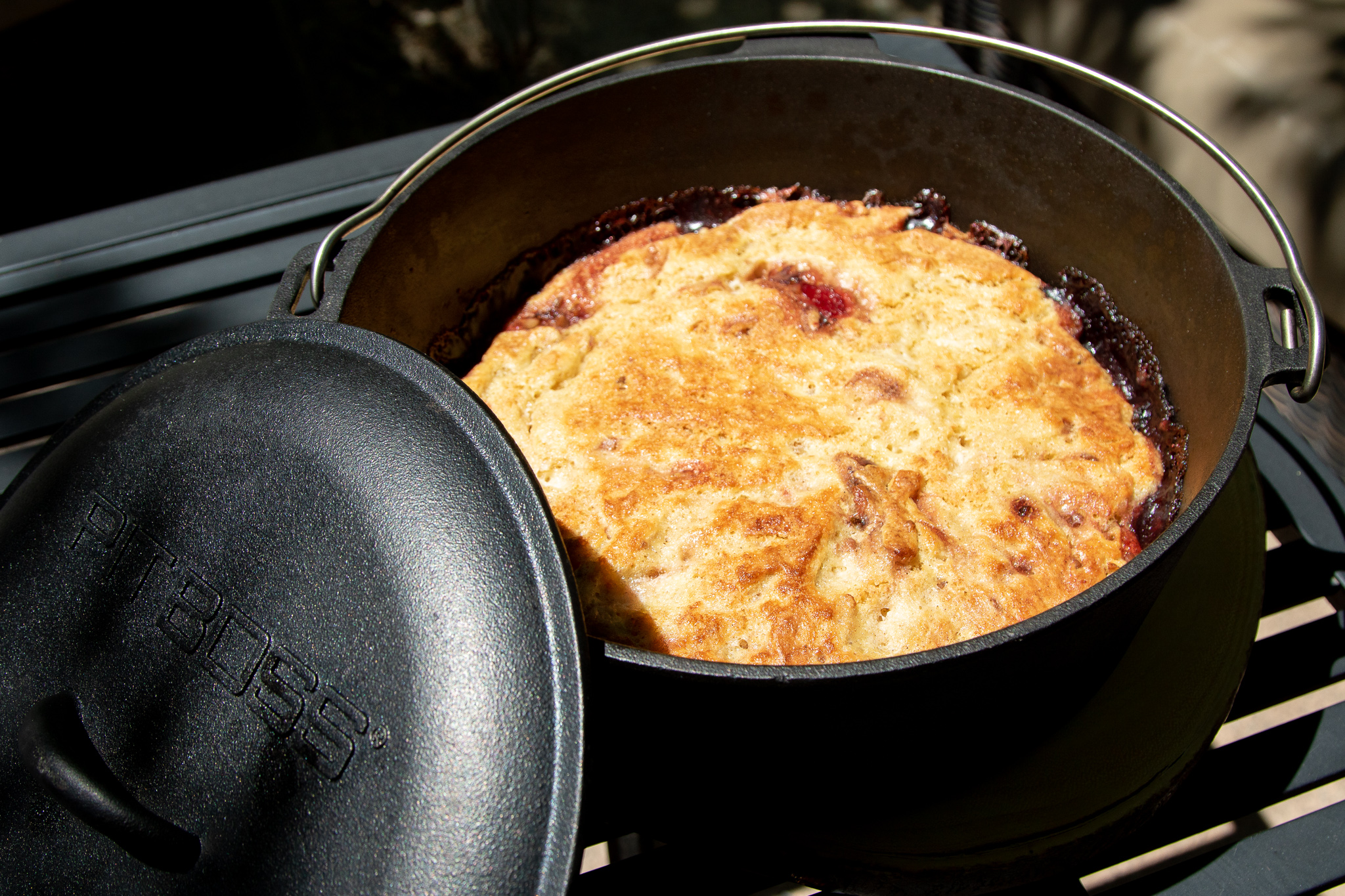 yummy campfire cherry crunch cobbler in black cast iron dutch oven with pit boss logo