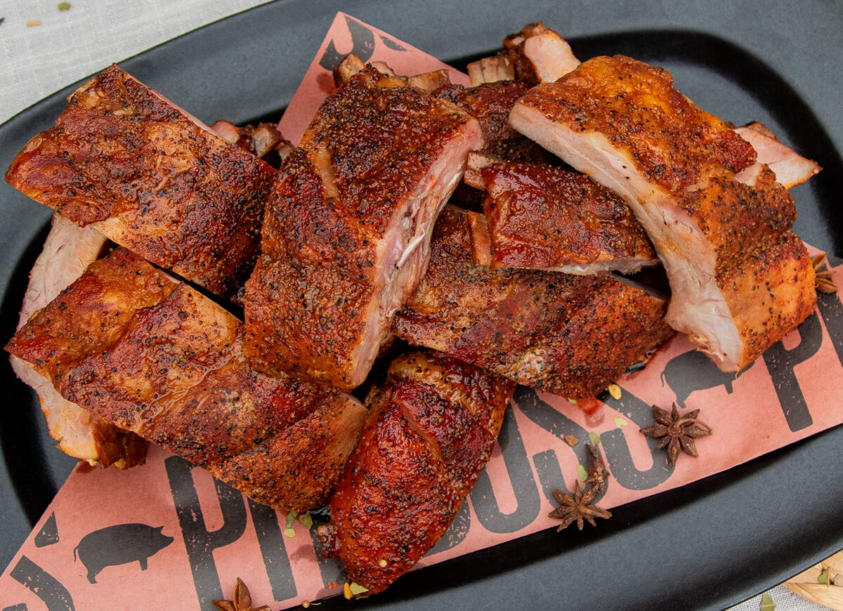 chai spiced and brined baby back ribs cooked on a pit boss pellet grill and plated on a black plate with fall spices like star anise