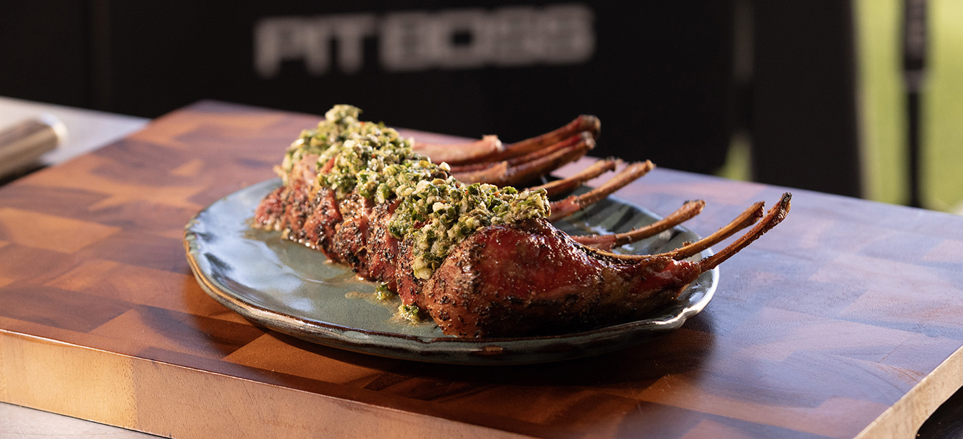smoked and seared rack of lamb with salsa verde cooked on a pit boss wood pellet grill served on a cutting board