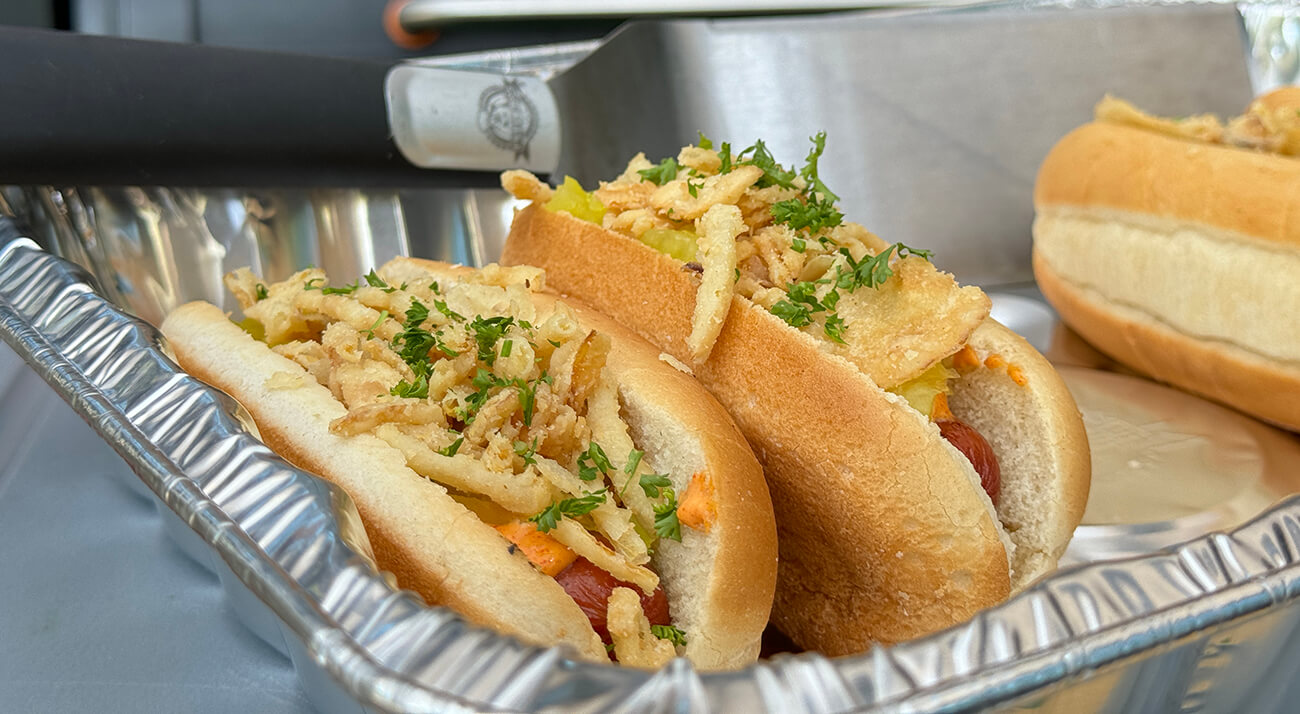 grilled crispy onion hot dog cooked on a pit boss wood pellet grill in an aluminum pan