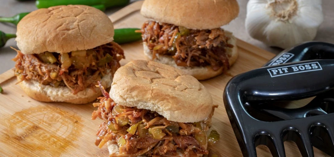 small sliders on wooden cutting board next to pit boss meat claws