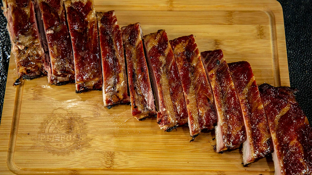 tasty looking Kansas City Style ribs, cut and placed on wooden cutting board