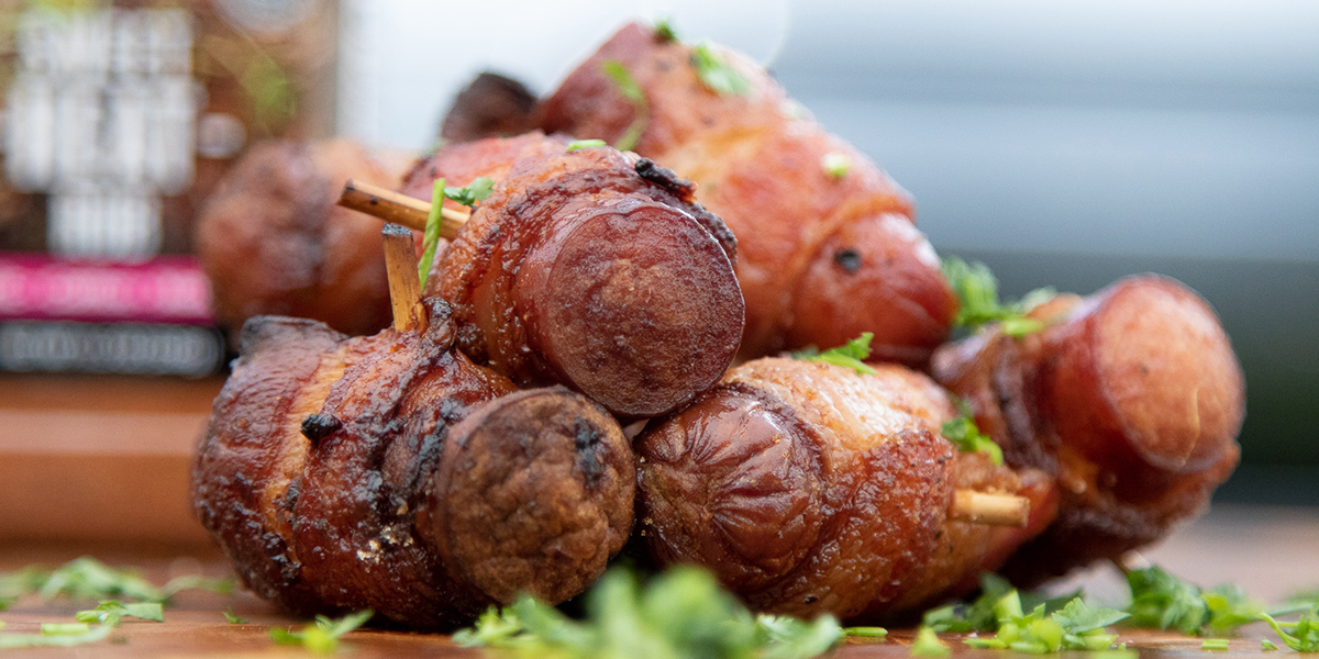 Little hot dogs wrapped in bacon and garnished with herbs