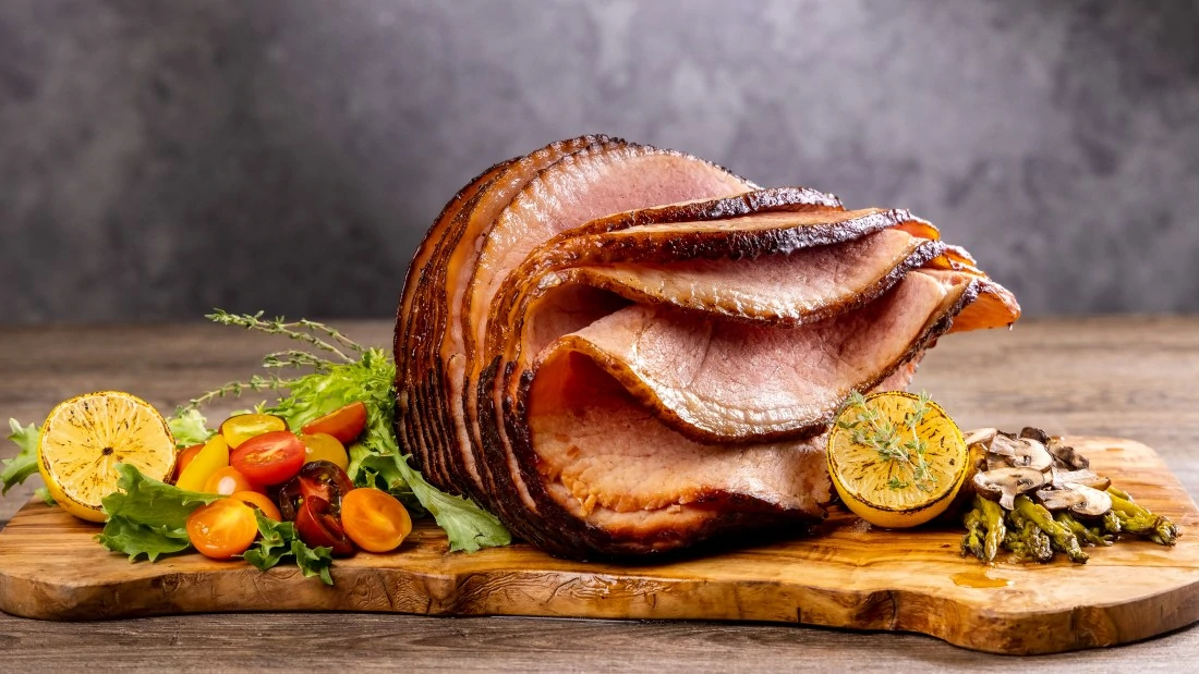 Smoked Ham sliced with garnishes on wooden board