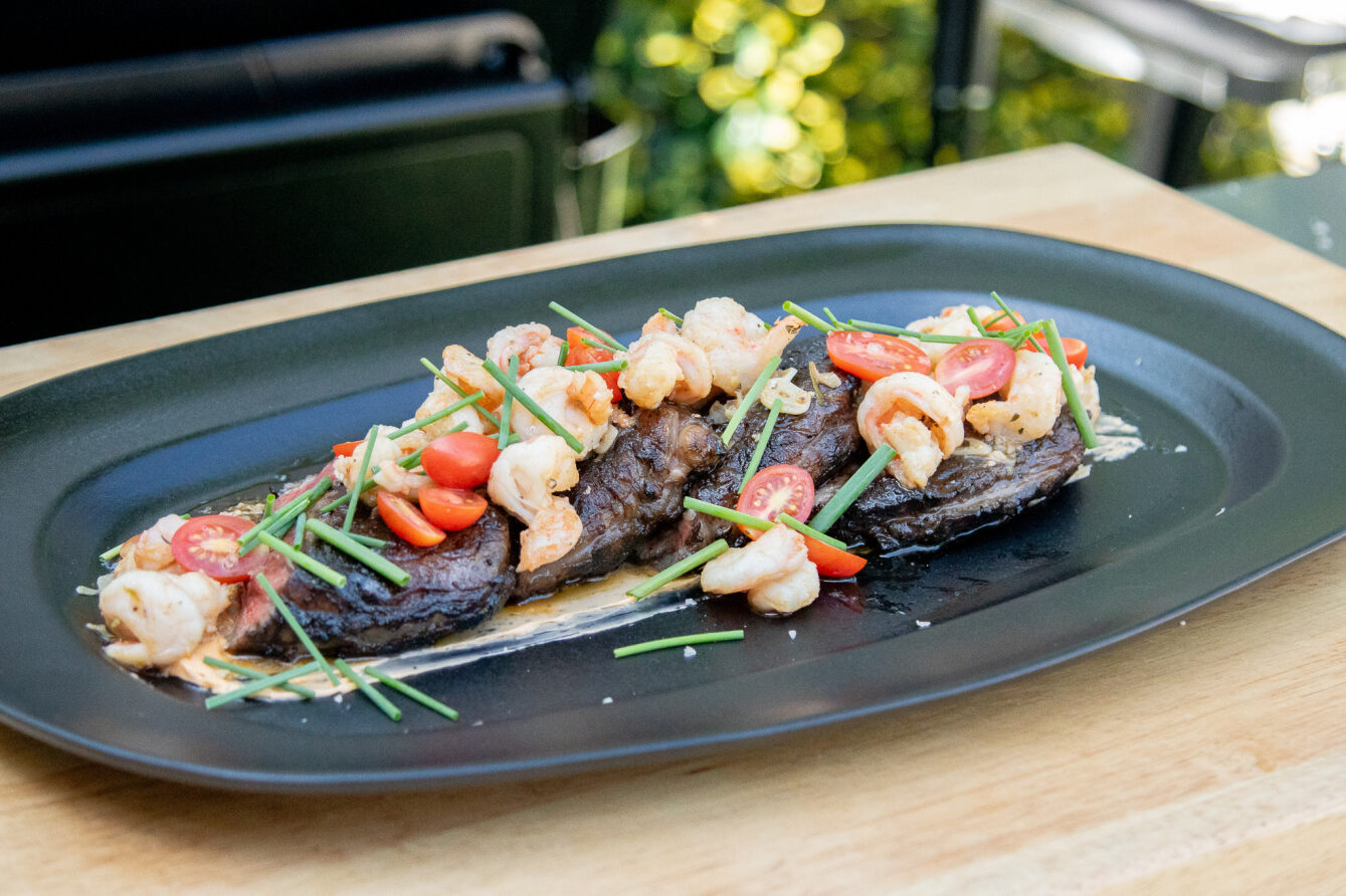 plated steak and shrimp grilled on a pit boss grill and topped with chives and cherry tomatoes