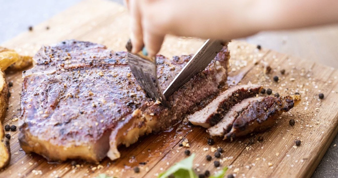 steak being cut on wood board
