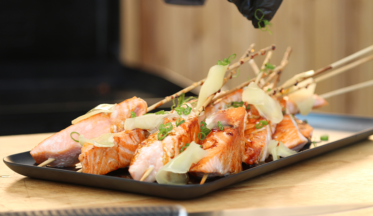 grilled salmon skewers on pit boss gas flat top griddle topped with sauce and garnishes
