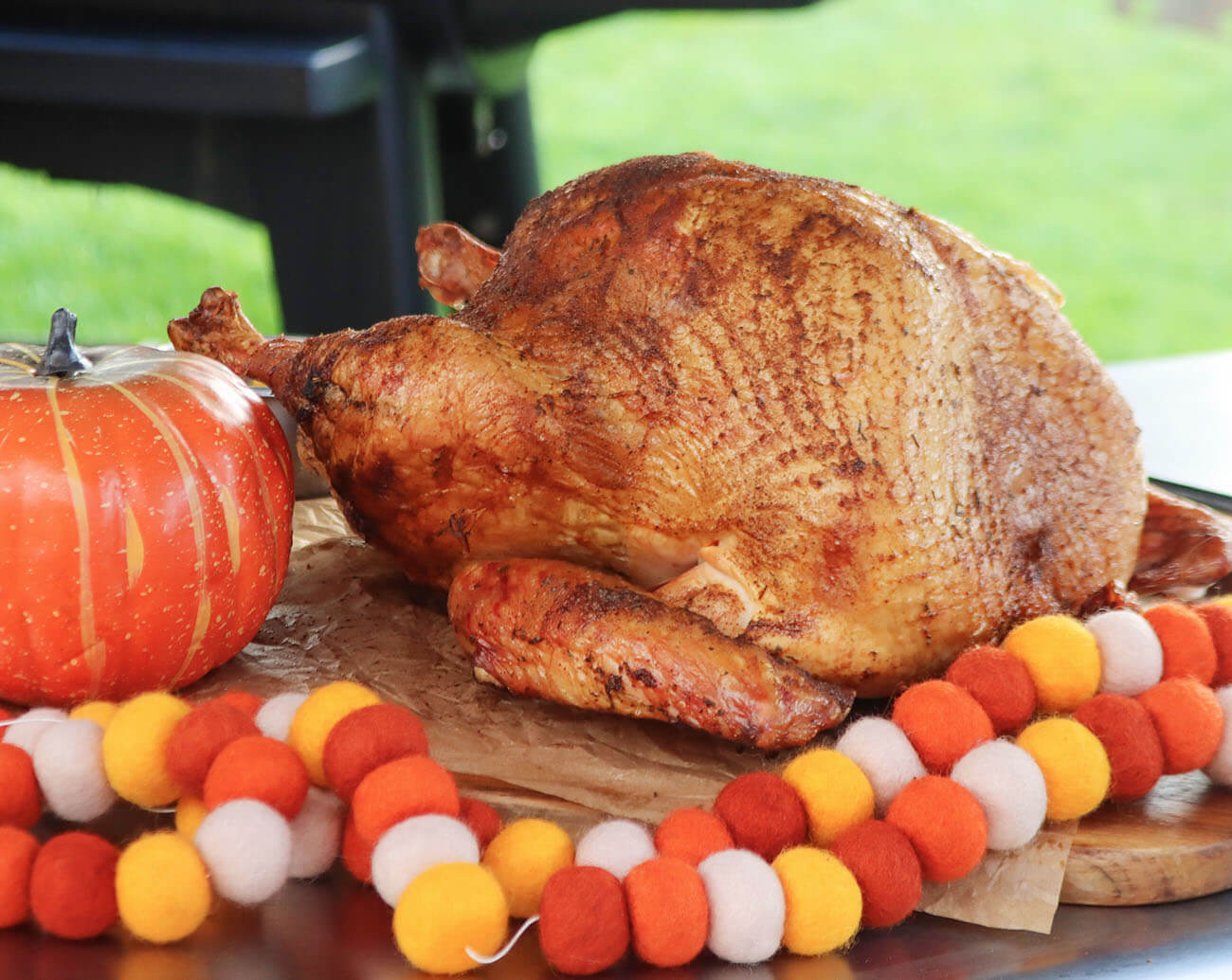 Easy Brined smoked turkey cooked on pit boss wood pellet grill plated next to pumpkin and thanksgiving decorations