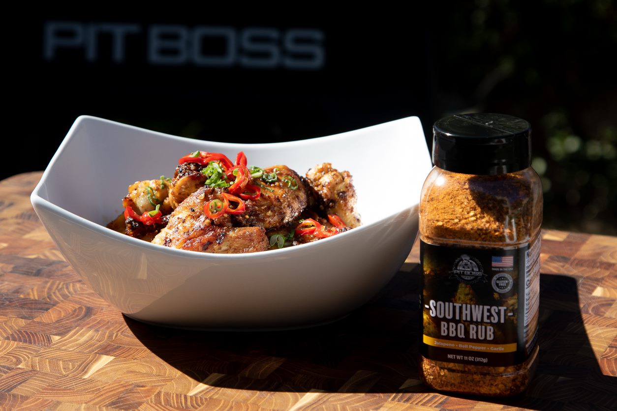 Seasoned chicken wings in a bowl next to Pit Boss Southwest BBQ Rub