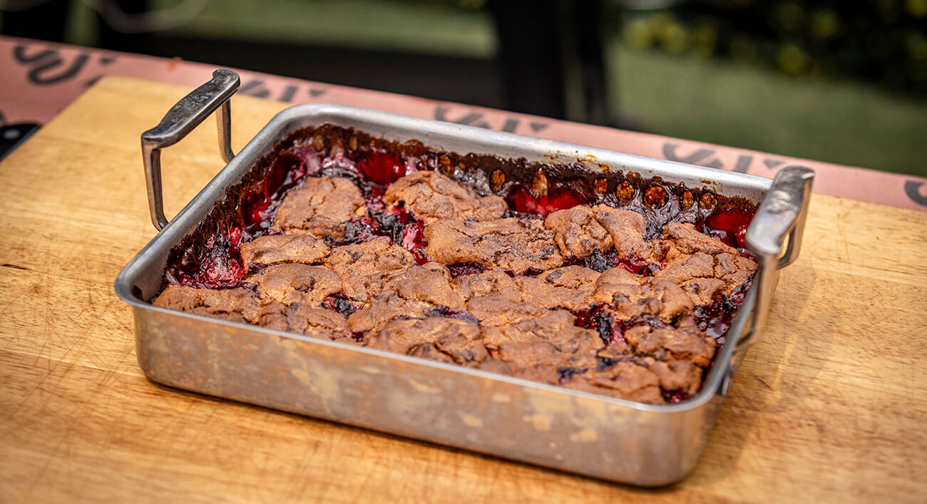 strawberry chocolate chip cookie cobbler baked on a pit boss wood pellet grill backyard camping recipe, served in metal tray