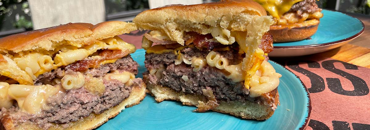 Stuffed Mac& Cheese burger cut in half on a teal plate