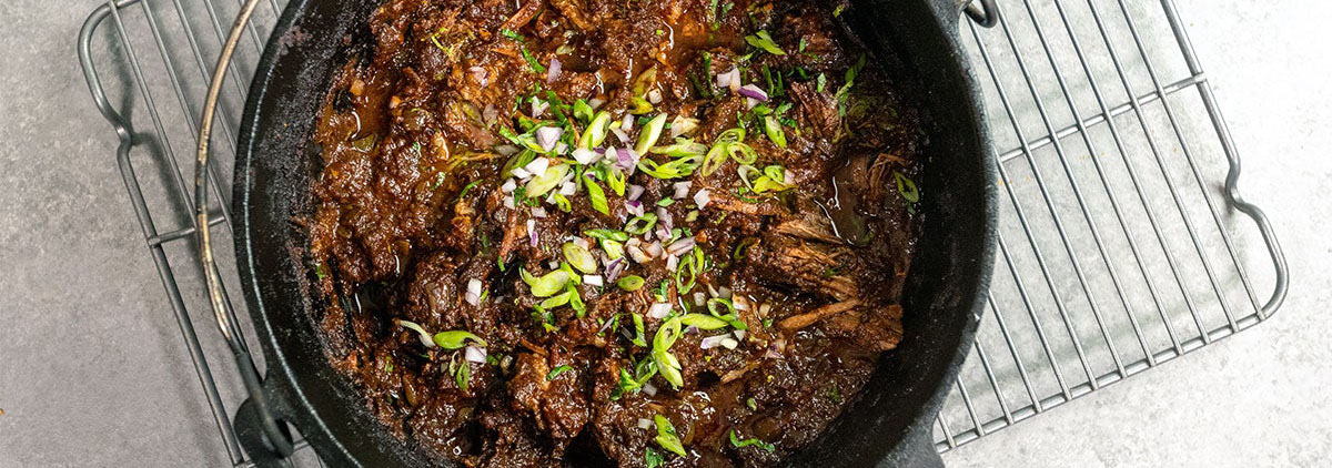 tasty looking Texas Chuck Roast garnished with herbs and green onions in cast iron oven