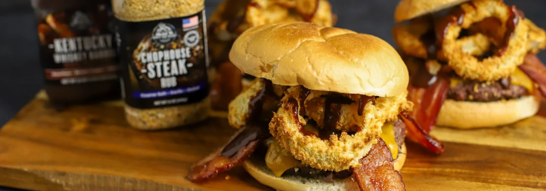 burgers on wooden board next to bottles of pit boss chophouse steak rub and kentucky whiskey bbq sauce