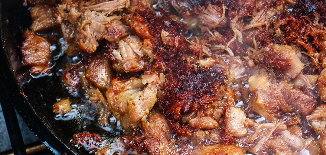 close up of steaming carnitas in pan