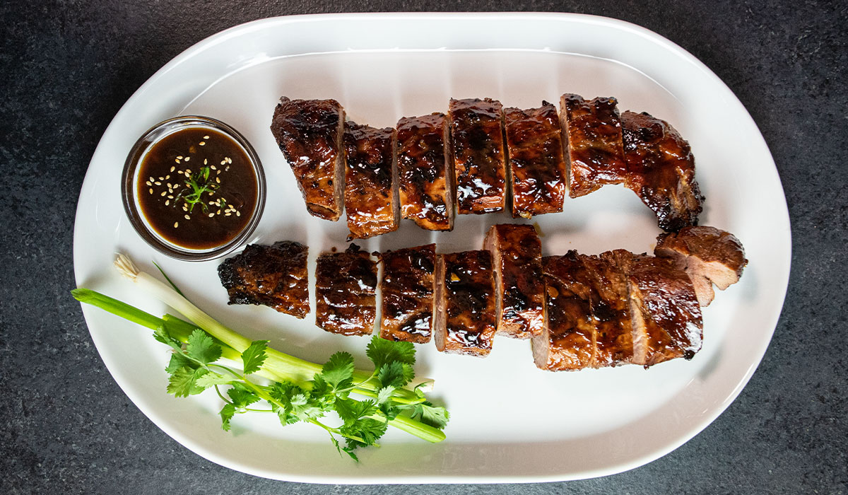 sliced tenderloin with sauce and garnishes served on a white plate