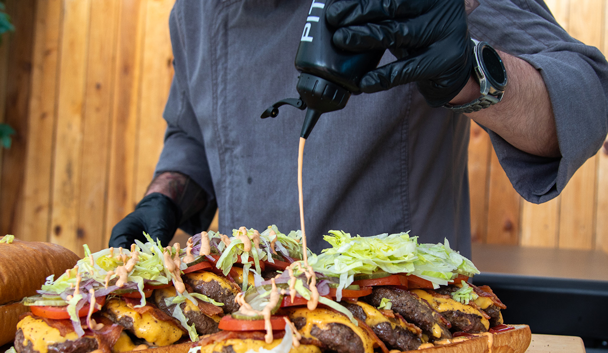 chipotle mayo sauce being drizzled on a shareable party burger cooked on a pit boss gas flat top griddle