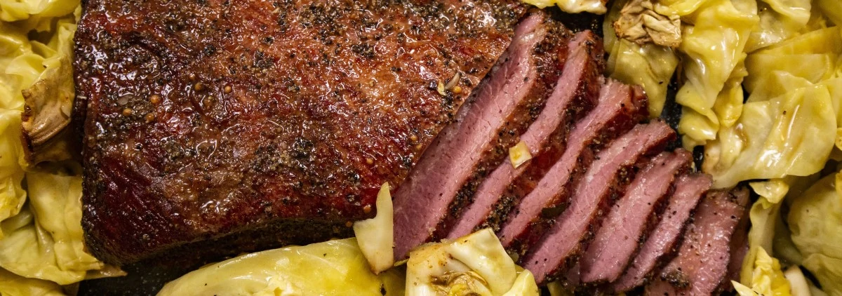 Close up of sliced corned beef surrounded by cooked green cabbage