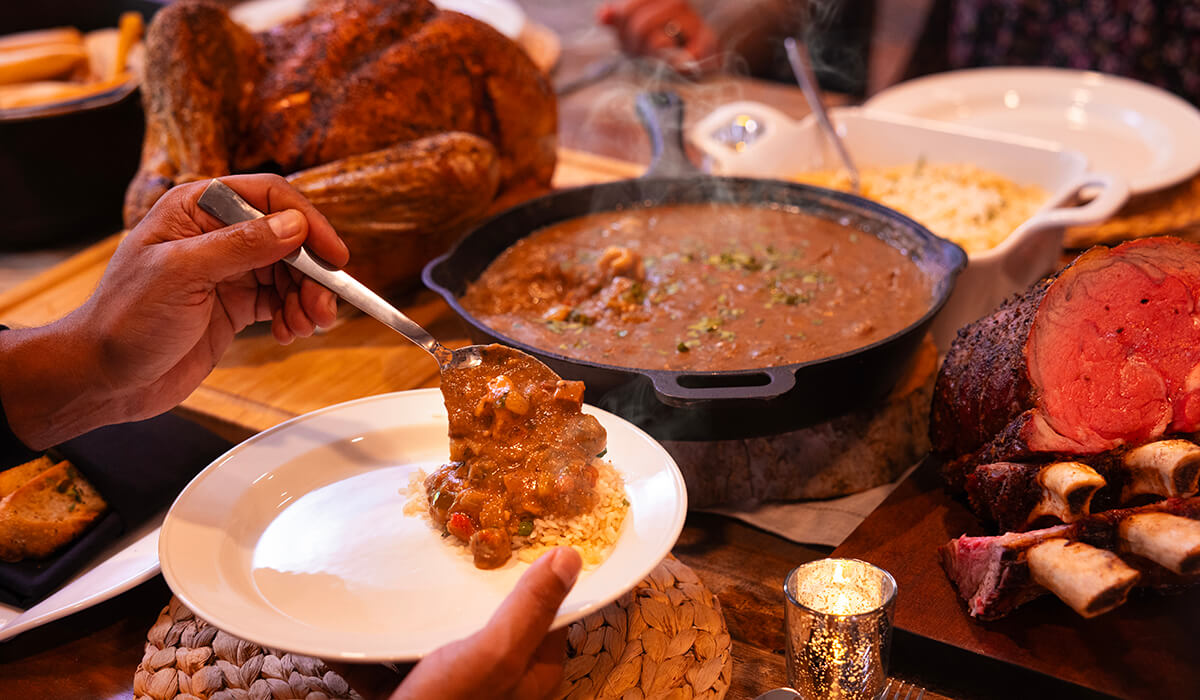 smoked gumbo being served over rice on holiday table with thanksgiving turkey and prime rib