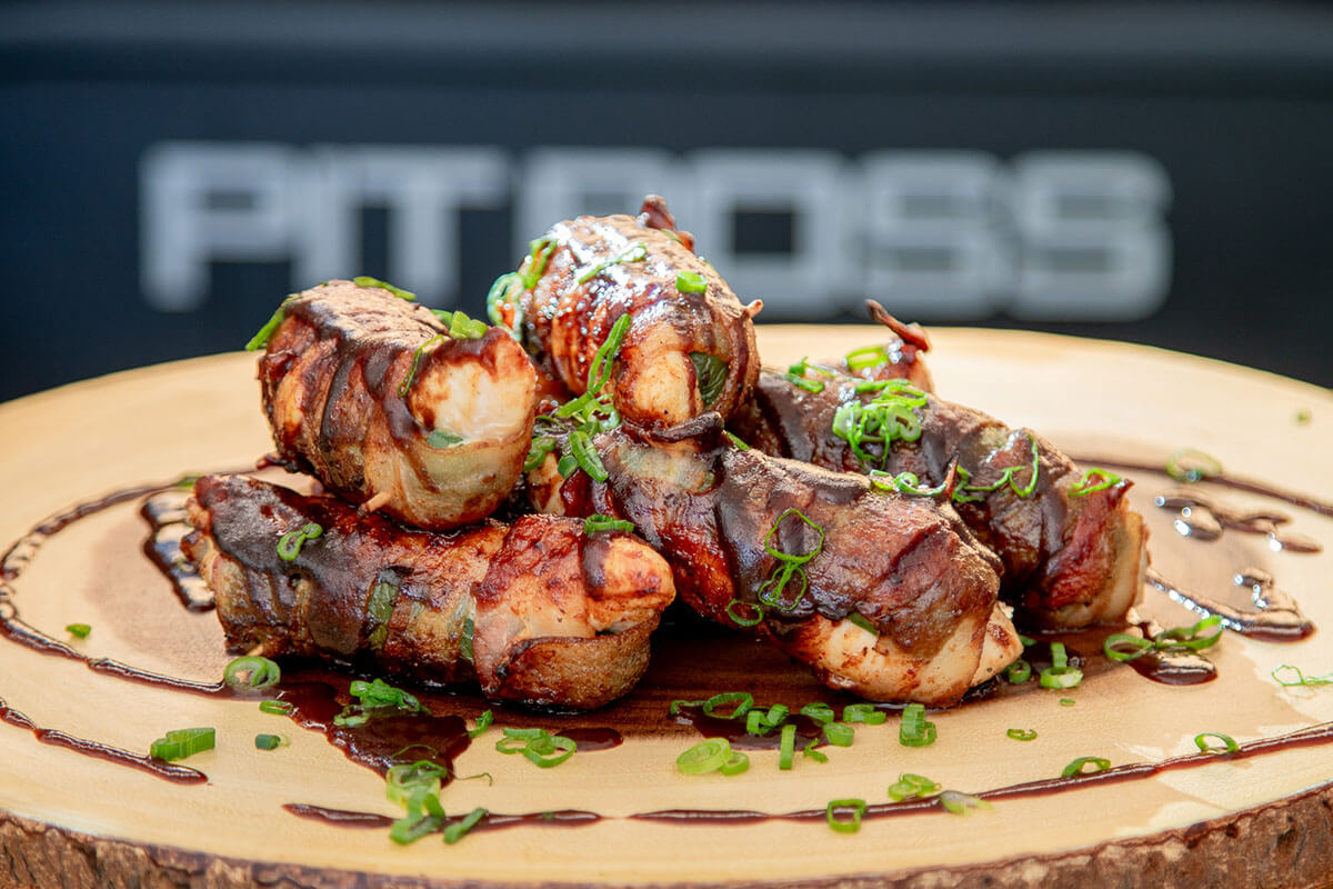 grilled and smoked jalapeno poppers served on wooden board and garnished with green onions and BBQ sauce