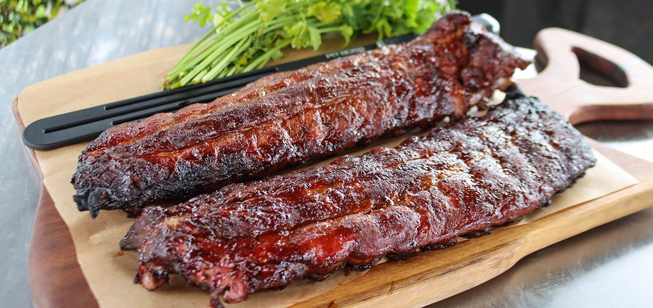 hanging smoked pork ribs served on a cutting board cooked on a pit boss charcoal smoker