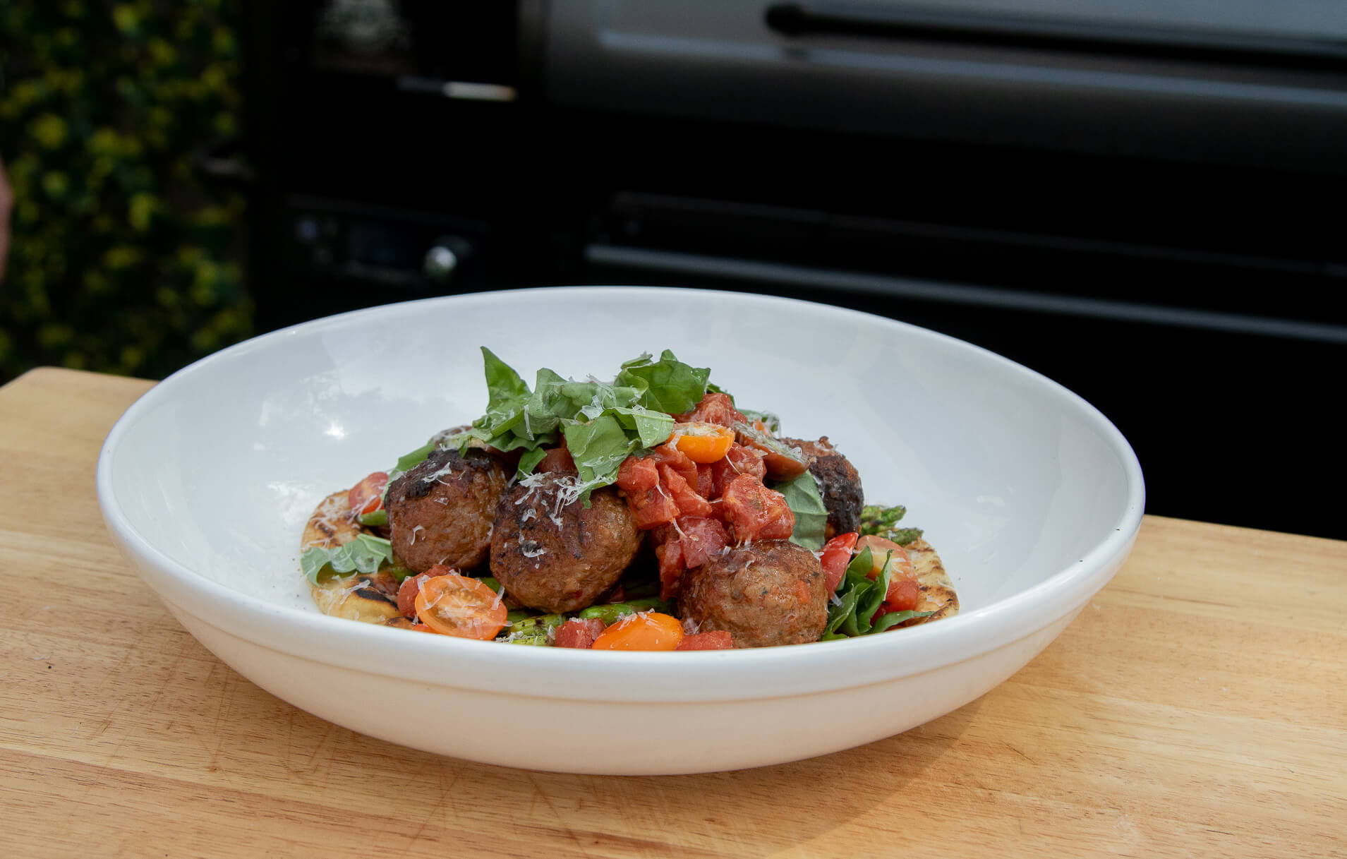 smoked meatballs on flatbread garnished with herbs and veggies