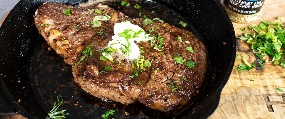 steak in cast iron pan with herbs and butter next to pit boss chophouse rub